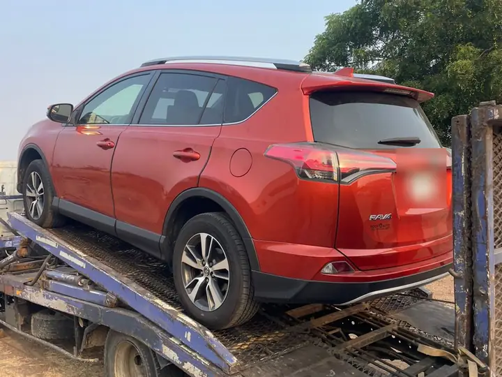 A red vehicle secured on a transport truck