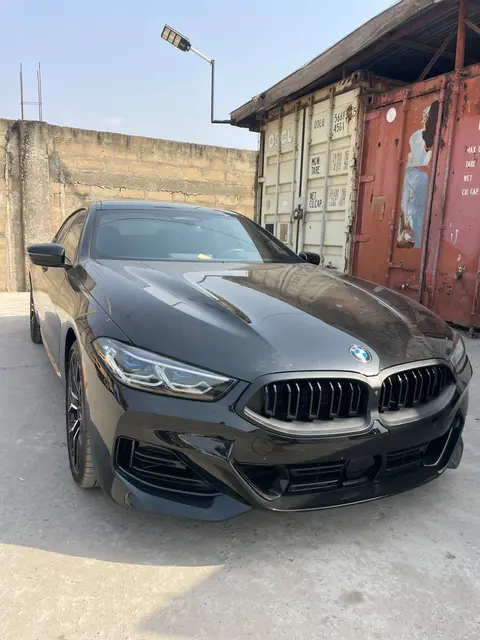 A grey BMW beside shipping containers