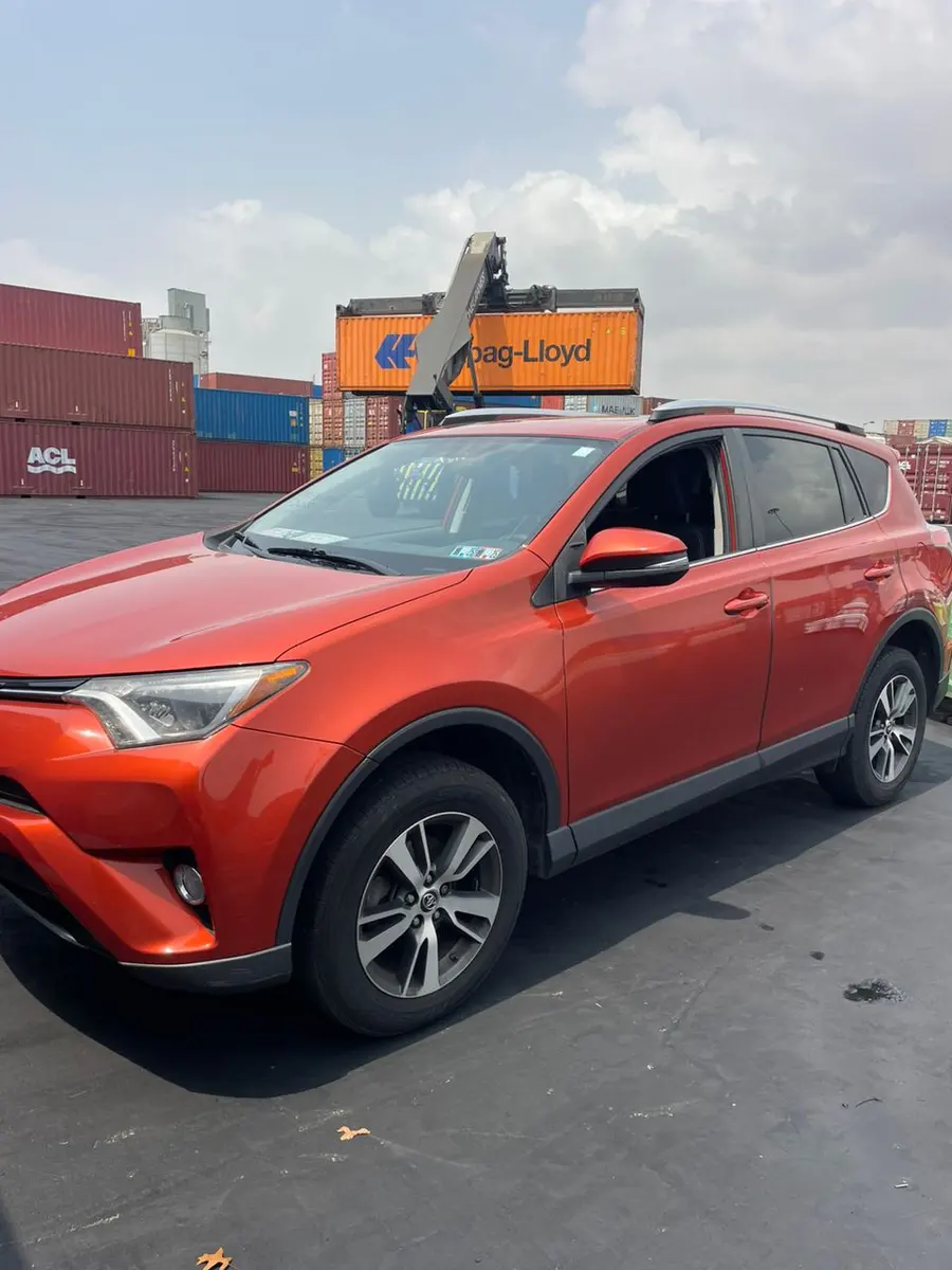 A red Toyota RAV4 beside the container stacks at Tema