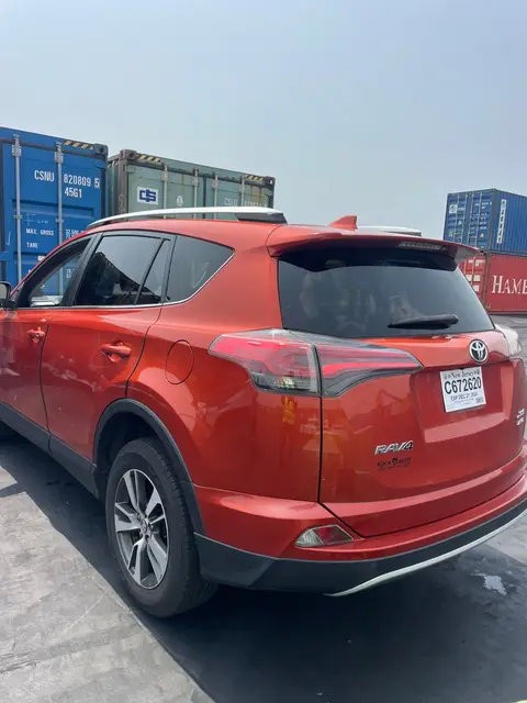 A red RAV4 near the container stacks