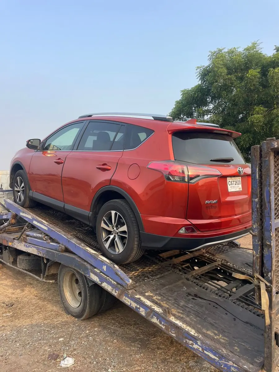 A red Toyota RAV4 loaded on a flatbed tow truck