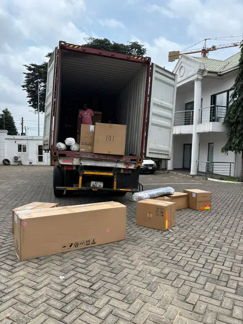 A truck carrying a shipping container in a delivery compound