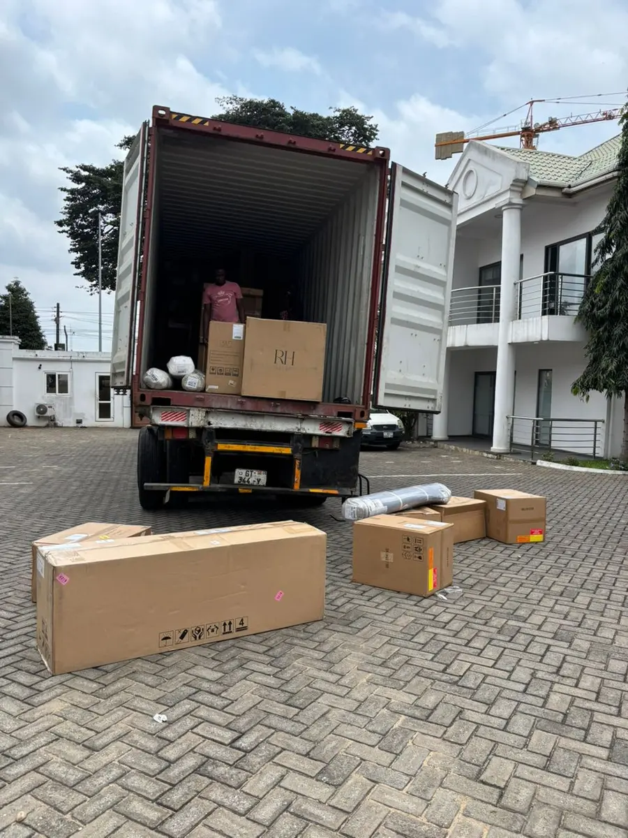 A truck carrying a shipping container in a delivery compound
